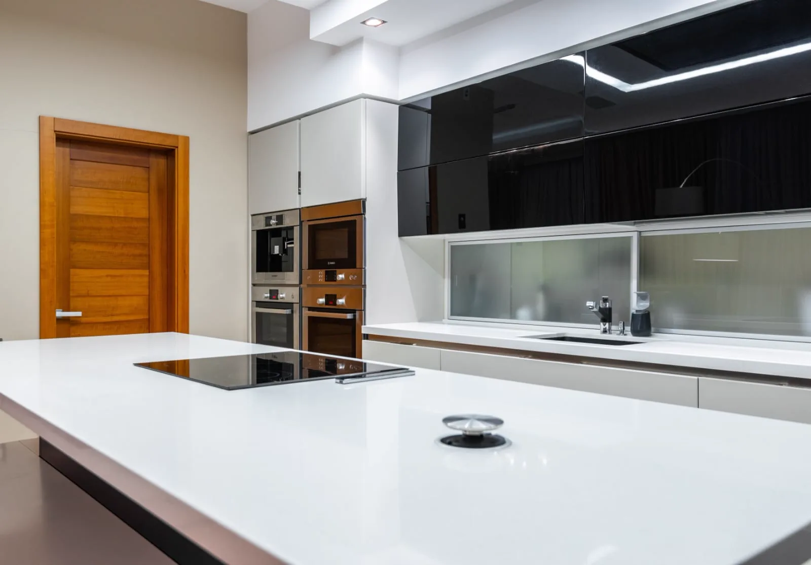 Cozinha com ilha em quartzo branco e recorte para cooktop